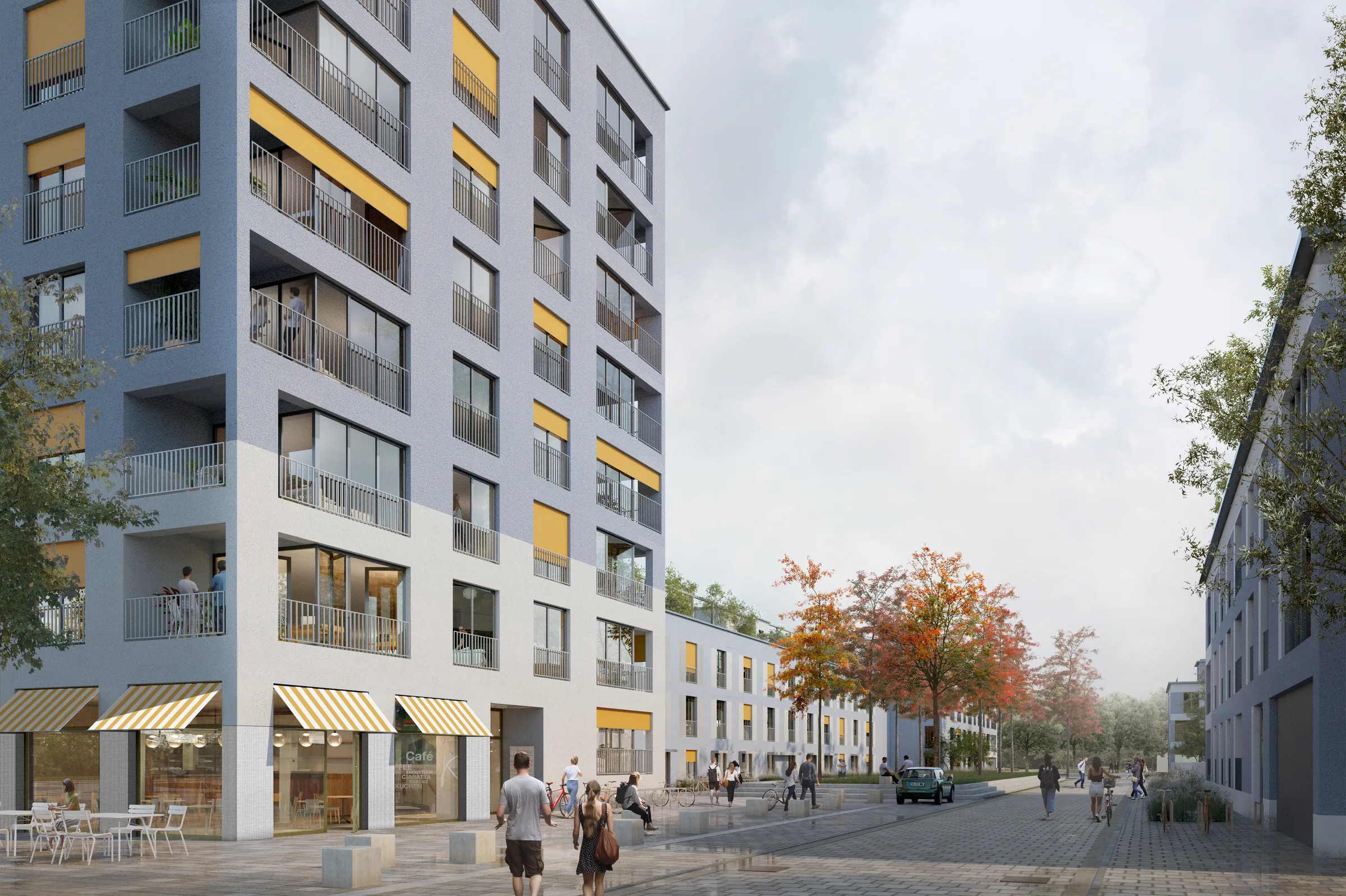 Straßenperspektive des Wohnquartiers Thermengarten in Erding — Eckgebäude mit Café im Erdgeschoss, blaugrau verputzte Fassade mit gelben Akzenten über hellem Fliesensockel am belebten Quartiersplatz